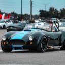 Man driving his convertible sports car with a blue panel.